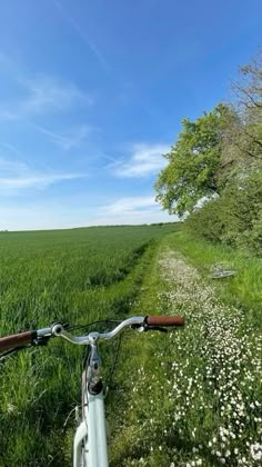 a bike is parked on the side of a dirt road in front of a field