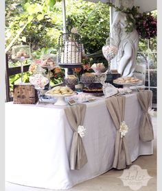 a table topped with lots of food next to a white statue in the middle of a garden