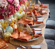 the table is set with orange napkins and gold place settings for an elegant dinner