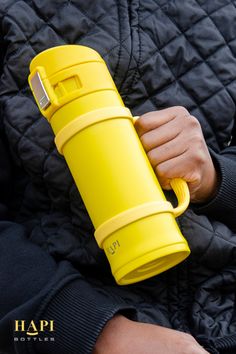 a person holding a yellow cup in their hand