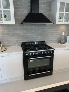 a black stove top oven sitting inside of a kitchen next to white cupboards and counter tops