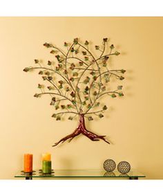 a metal tree with lots of leaves on it's branches is mounted to the wall