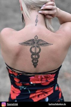 the back of a woman's neck with a medical symbol tattoo on her left shoulder