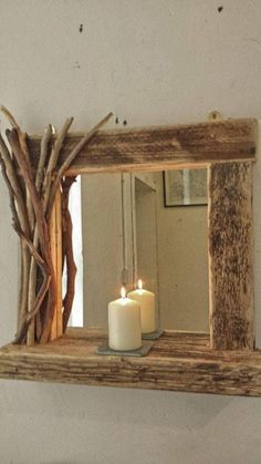 a candle is lit in front of a mirror with driftwood branches on the shelf