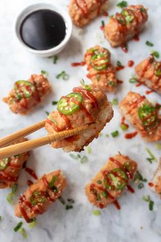 chopsticks holding up food with sauce and green onions