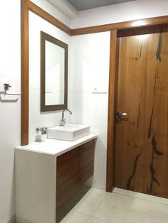 a bathroom with a sink, mirror and wooden door