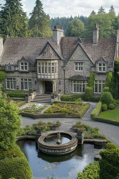 a large house surrounded by lush green trees and bushes with a fountain in the middle