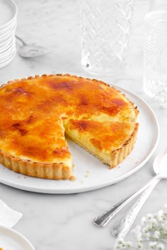 a cheese pie on a white plate next to silverware