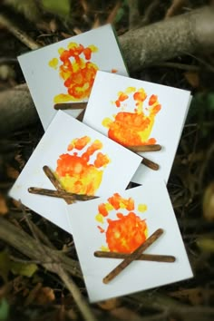 four cards with handprints on them sitting in the grass next to some sticks