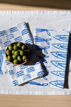 a bowl of olives on a table with two napkins next to it and a fork