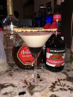 a martini glass sitting on top of a marble counter next to bottles and condiments