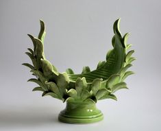 a green vase that has some plants in it