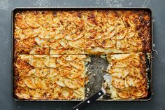 a baking pan filled with apple slices on top of a table next to a knife