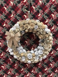 a christmas wreath made out of rolled up paper flowers on a red and black checkered table cloth