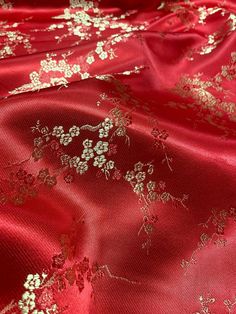 red and gold fabric with white flowers on the top, as if it were brocaded