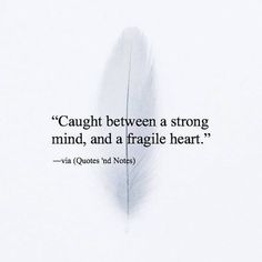 a feather with a quote on it that says, caught between a strong mind and a fragile heart