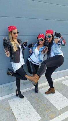 three women posing for the camera with their arms in the air and wearing bandanas