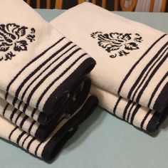 three towels folded on top of each other with black and white striped trimmings