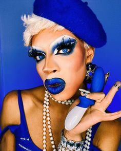 a woman with blue makeup holding a cell phone