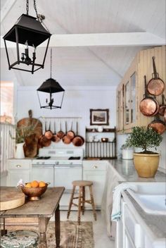 a kitchen filled with lots of counter space and hanging lights over the stove top oven