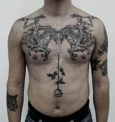 a man with tattoos on his chest standing in front of a white wall