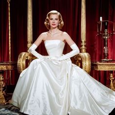 a woman in a white dress sitting on a gold chair with her hands on her hips