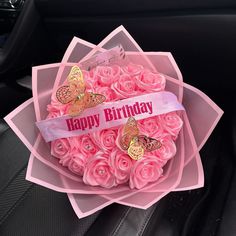 a bouquet of pink roses in a car with a happy birthday ribbon on it's lap