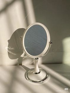 a white table top with a mirror on it's side and the shadow of a wall behind it