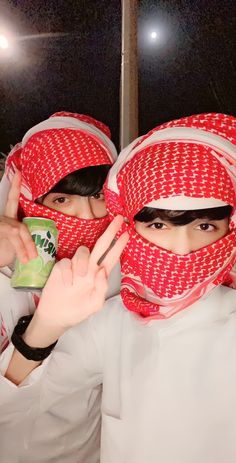 two people wearing red and white head coverings with their fingers up in the air