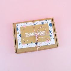 a thank you card in a box on a pink background