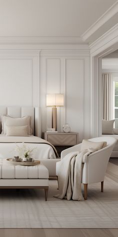 a large white bed sitting in a bedroom next to a chair and table on top of a hard wood floor