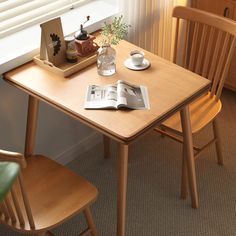 a wooden table with two chairs next to it and a magazine on top of the table