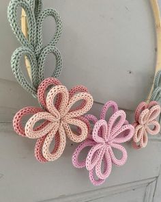 three crocheted flowers are hanging from a hoop