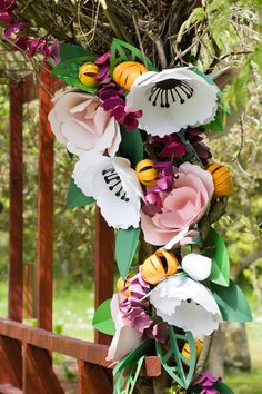 paper flowers are hanging from a wooden fence