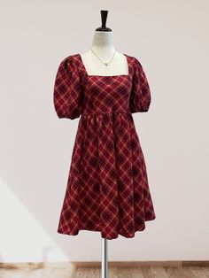 Featuring a checkered plaid print on woven fabric, this mini dress is perfect for the fall and winter months. The square neckline and short puff sleeves add a touch of femininity, while the babydoll waistline and smocking detail on the back provide a comfortable and flattering fit. Complete with a back tie detail and convenient side pockets, this dress is the perfect choice for the holiday season.