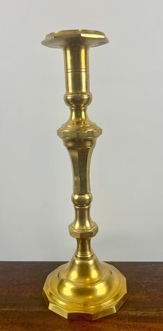 a brass candle holder sitting on top of a wooden table