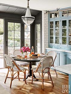 a dining room table with four chairs and a light fixture hanging from the ceiling over it