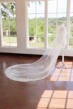 a wedding dress on display in front of windows