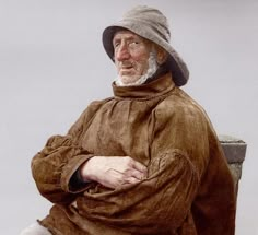 an old man sitting on a bench wearing a hat and brown coat with his arms crossed