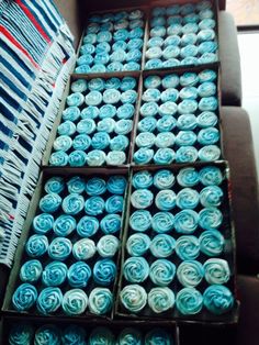 several boxes filled with blue and white cupcakes sitting on top of a couch