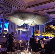 a group of people sitting at tables in a room with tall ceilings and flowers on the ceiling