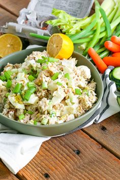 a bowl filled with food sitting on top of a table next to vegetables and lemon wedges