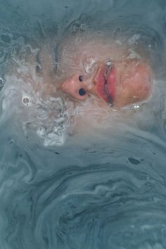 a woman is floating in the water with her head above the water's surface