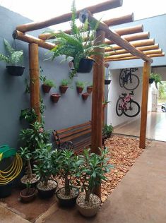 a wooden bench sitting under a pergolated roof next to potted plants and trees