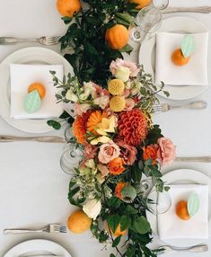 the table is set with plates, silverware and flowers