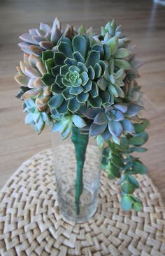 a glass vase filled with lots of green flowers on top of a table next to a wicker place mat