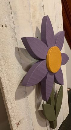 a purple flower is mounted to the side of a wall