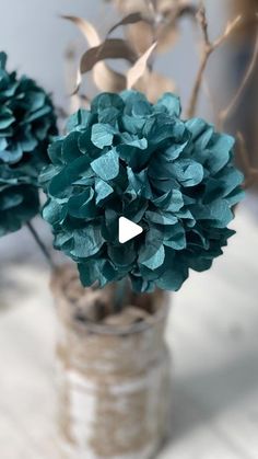 two vases filled with green flowers on top of a white cloth covered tablecloth