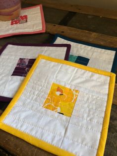 three quilted placemats sitting on top of a wooden table next to a cup