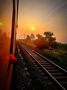 the sun is setting over railroad tracks as seen from inside a train car at dusk